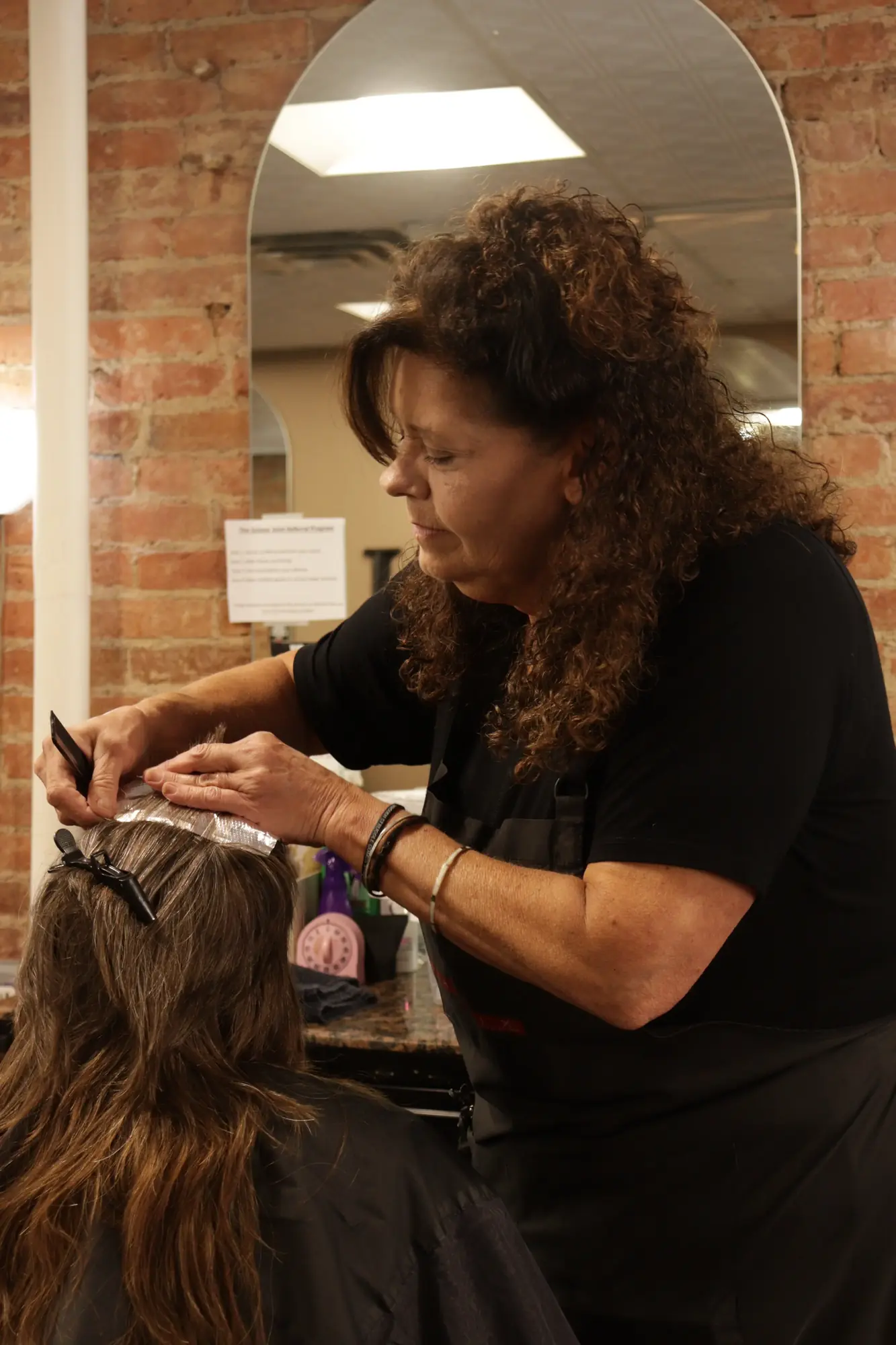 A stylist carefully applying color to a client’s hair