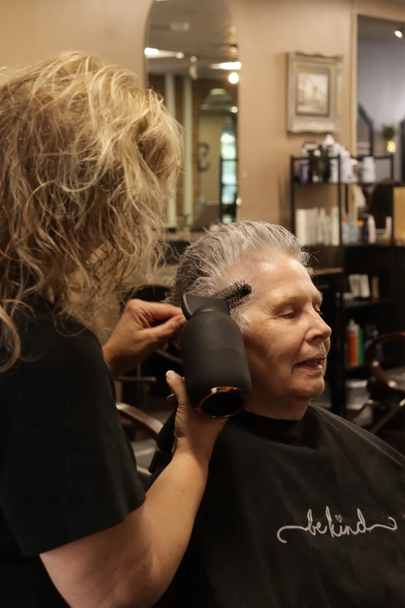 A stylist blow-drying a client’s hair inside The Scissor Joint